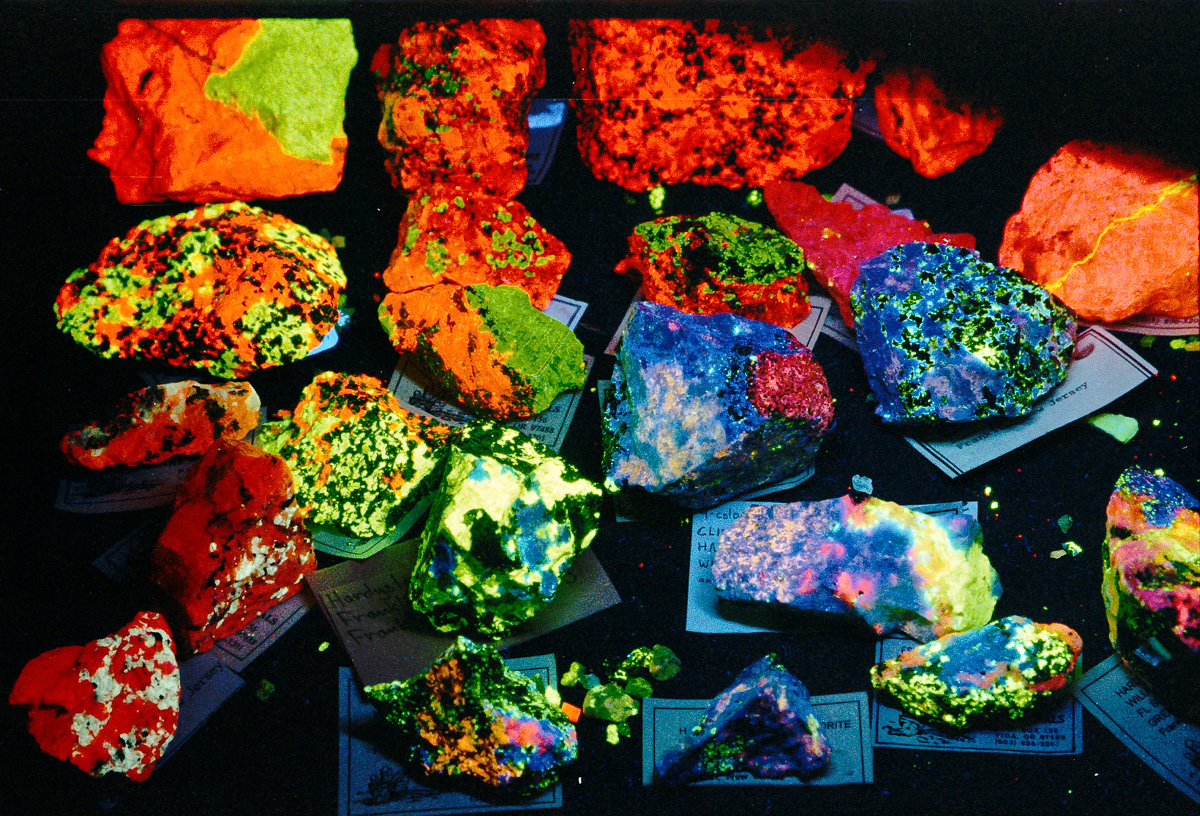 Large variety of fluorescent minerals layer out on a flat surface.